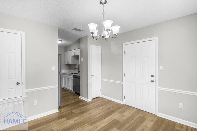 197 Sequoia Cir, Hinesville, GA 31313 - unfurnished dining area with a notable chandelier, baseboards, a sink, and wood finished floors