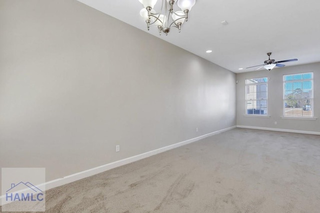 carpeted empty room featuring ceiling fan with notable chandelier