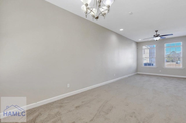 carpeted spare room featuring ceiling fan with notable chandelier