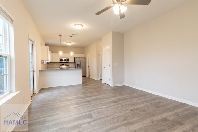 kitchen with plenty of natural light, white cabinetry, kitchen peninsula, and stainless steel appliances