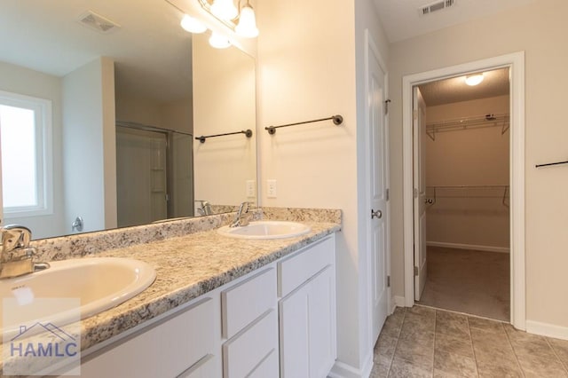 bathroom featuring tile patterned floors, vanity, and a shower with door