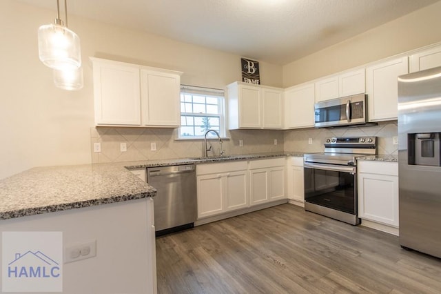 kitchen with dark wood-type flooring, hanging light fixtures, sink, appliances with stainless steel finishes, and white cabinetry