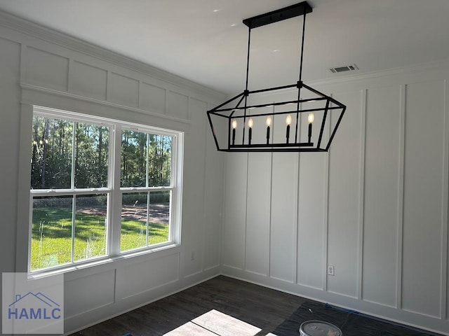 unfurnished dining area featuring dark hardwood / wood-style flooring, ornamental molding, and a chandelier