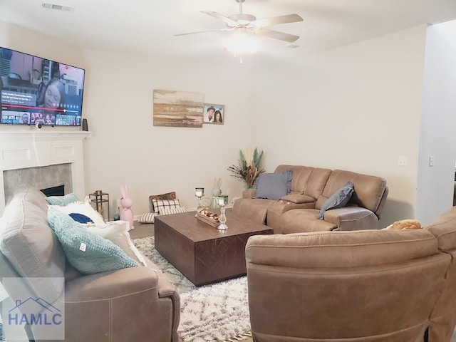 living room featuring a tiled fireplace and ceiling fan