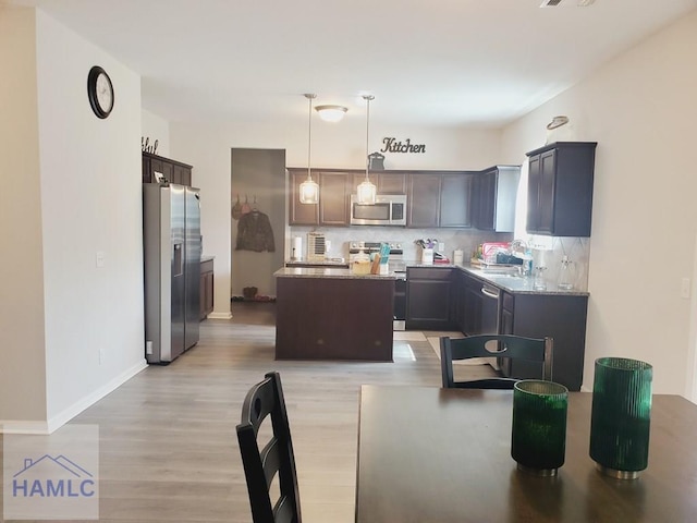 kitchen with a kitchen island, appliances with stainless steel finishes, decorative light fixtures, decorative backsplash, and dark brown cabinets