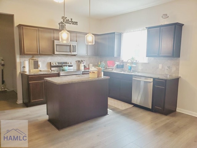 kitchen with decorative light fixtures, a kitchen island, decorative backsplash, and appliances with stainless steel finishes