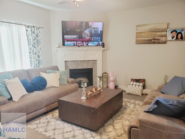 living room with a tile fireplace and hardwood / wood-style floors