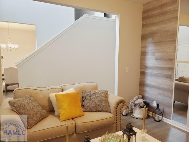 living room featuring wood-type flooring, wooden walls, and an inviting chandelier