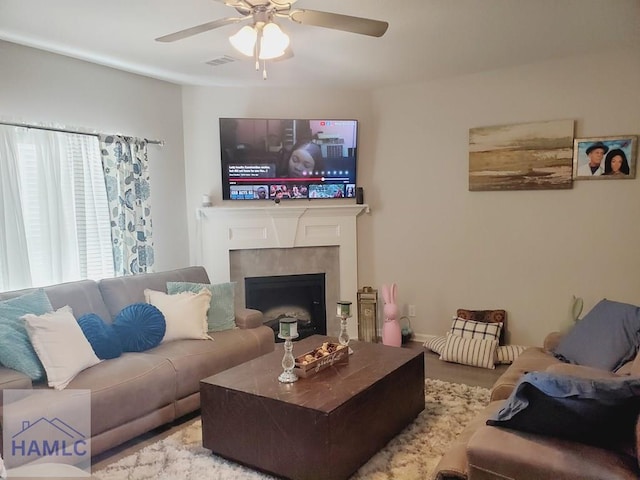 living room with a tiled fireplace and ceiling fan