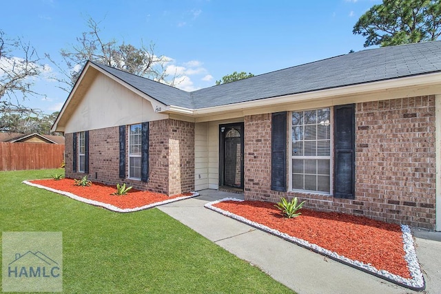 single story home with an attached garage, brick siding, driveway, and a front lawn