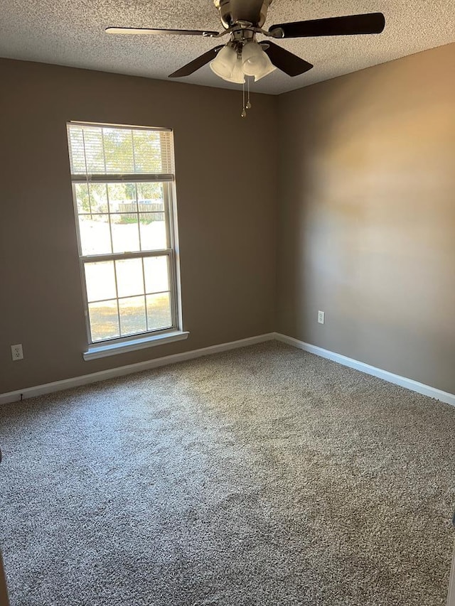 carpeted empty room with ceiling fan, a healthy amount of sunlight, and a textured ceiling