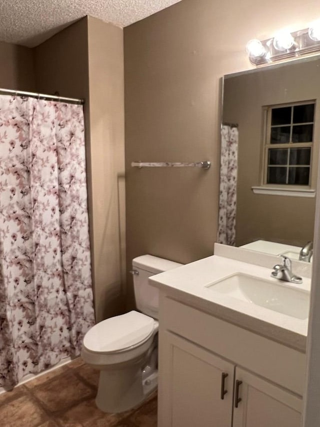 bathroom with vanity, toilet, and a textured ceiling