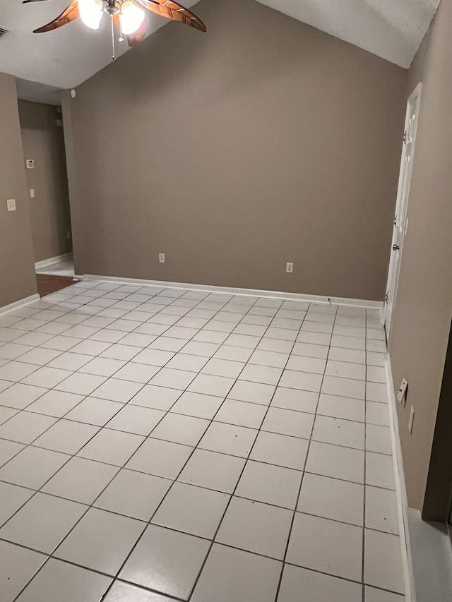 empty room featuring ceiling fan, light tile patterned floors, and vaulted ceiling