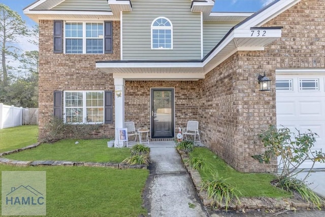 732 Waterlily Ct, Hinesville, GA 31313 - view of exterior entry featuring a garage, brick siding, fence, and a yard
