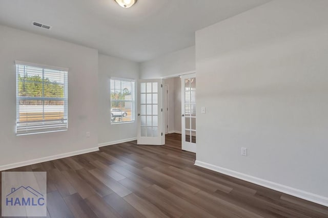 empty room with dark wood-style floors, baseboards, visible vents, and french doors