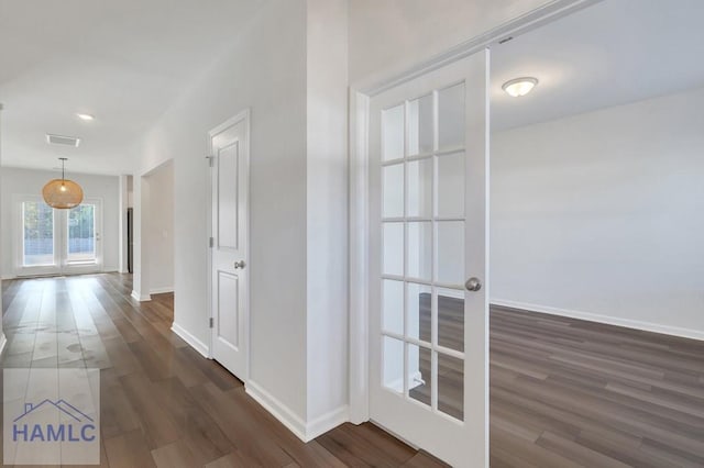 corridor with baseboards, visible vents, and dark wood-style flooring