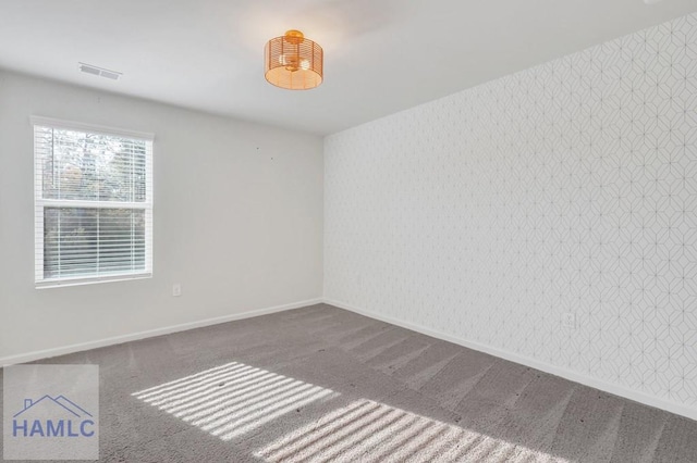 unfurnished room featuring carpet, visible vents, baseboards, and wallpapered walls