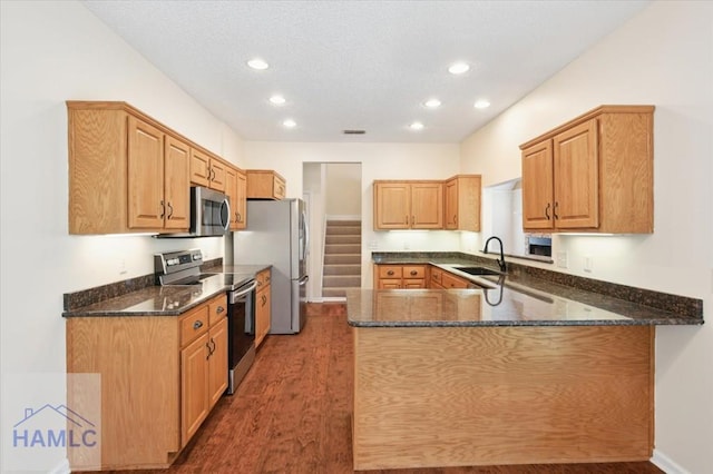 301 Marsh View Dr, Richmond Hill, GA 31324 - kitchen featuring stainless steel appliances, wood finished floors, dark stone counters, a peninsula, and recessed lighting