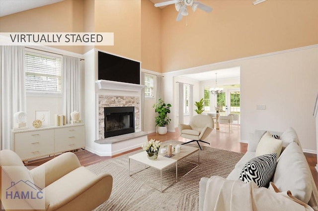 301 Marsh View Dr, Richmond Hill, GA 31324 - living room featuring wood finished floors, a towering ceiling, a ceiling fan, a fireplace, and a chandelier