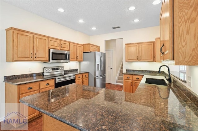 301 Marsh View Dr, Richmond Hill, GA 31324 - kitchen with stainless steel appliances, a peninsula, a textured ceiling, recessed lighting, and dark stone countertops