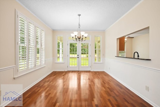 301 Marsh View Dr, Richmond Hill, GA 31324 - unfurnished dining area featuring a chandelier, crown molding, wood finished floors, french doors, and a textured ceiling