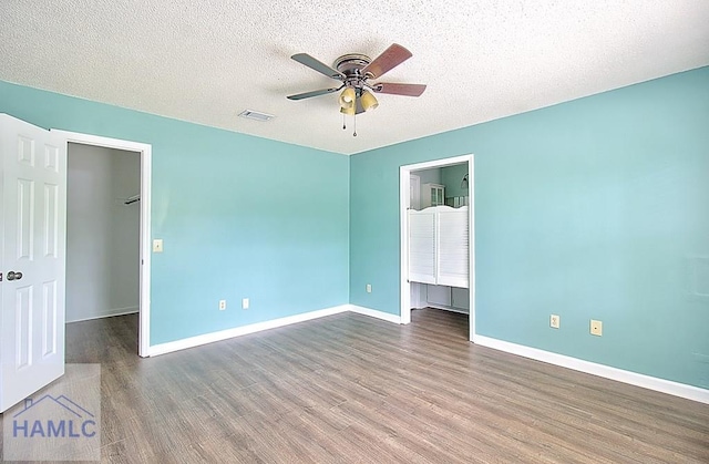 unfurnished bedroom featuring ceiling fan, dark hardwood / wood-style floors, a textured ceiling, a spacious closet, and a closet