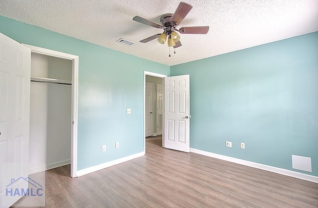 unfurnished bedroom featuring ceiling fan, a closet, light hardwood / wood-style floors, and a textured ceiling