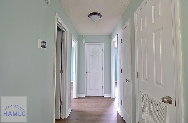 hall featuring dark wood-type flooring and a textured ceiling