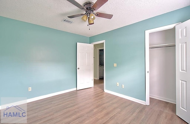 unfurnished bedroom featuring hardwood / wood-style floors, a textured ceiling, and a closet