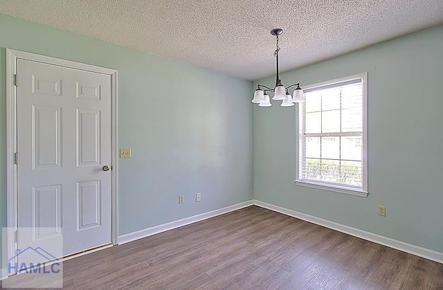 unfurnished room with hardwood / wood-style flooring, a chandelier, and a textured ceiling