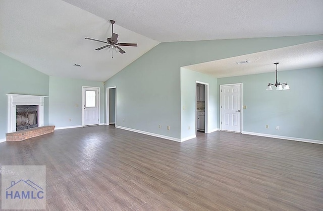 unfurnished living room with vaulted ceiling, ceiling fan with notable chandelier, a brick fireplace, dark wood-type flooring, and a textured ceiling