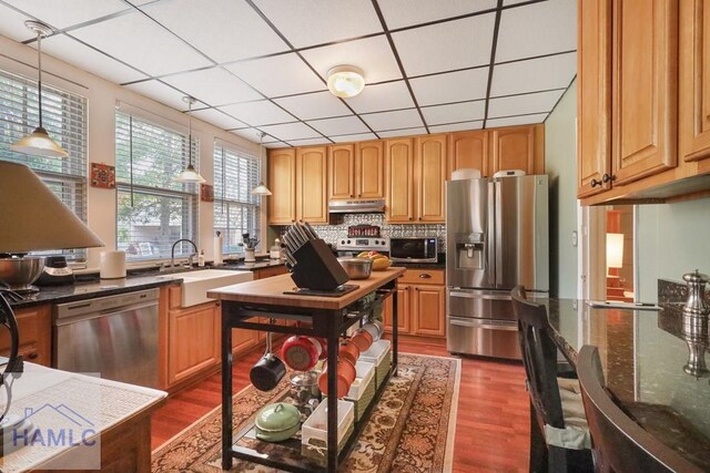 661 E Plum St, Jesup, GA 31546 - kitchen with stainless steel appliances, under cabinet range hood, dark wood finished floors, a drop ceiling, and hanging light fixtures