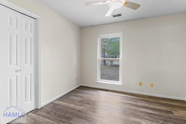 unfurnished room with a ceiling fan, visible vents, baseboards, and wood finished floors