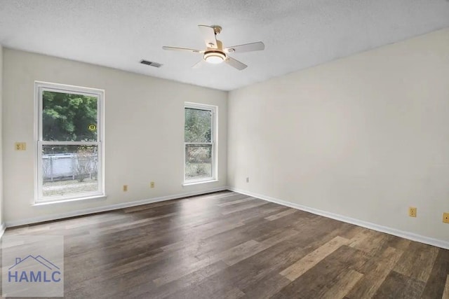 empty room featuring a textured ceiling, wood finished floors, a ceiling fan, visible vents, and baseboards