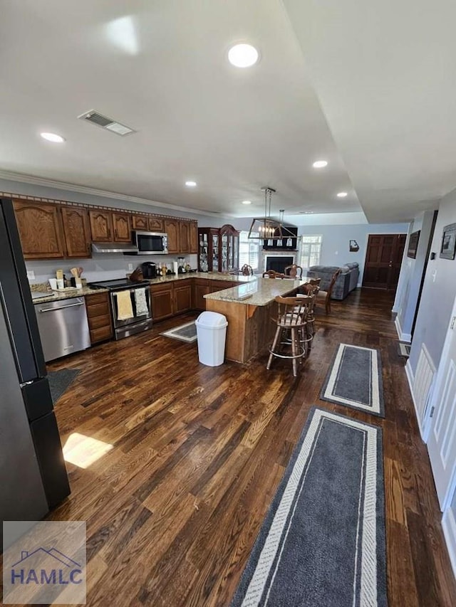 kitchen featuring dark hardwood / wood-style floors, a center island, stainless steel appliances, and a breakfast bar area