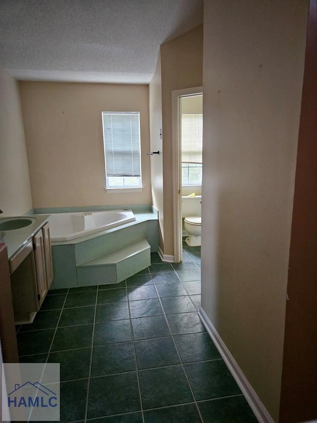 bathroom with a textured ceiling, toilet, tile patterned floors, a tub, and vanity