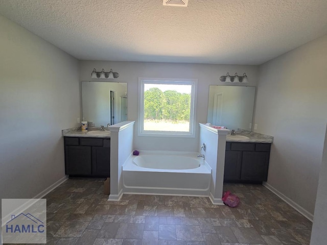 132 Turpentine Trl, Hinesville, GA 31313 - full bath with a textured ceiling, a garden tub, two vanities, and baseboards