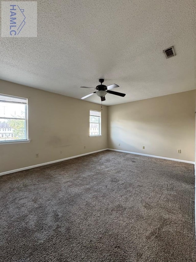 unfurnished room featuring dark colored carpet and a healthy amount of sunlight