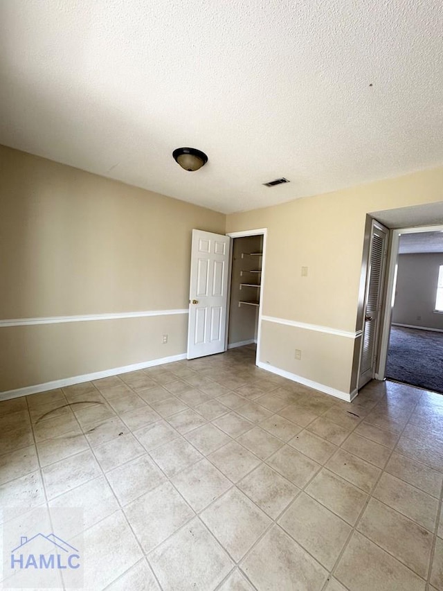 spare room with light tile patterned floors and a textured ceiling