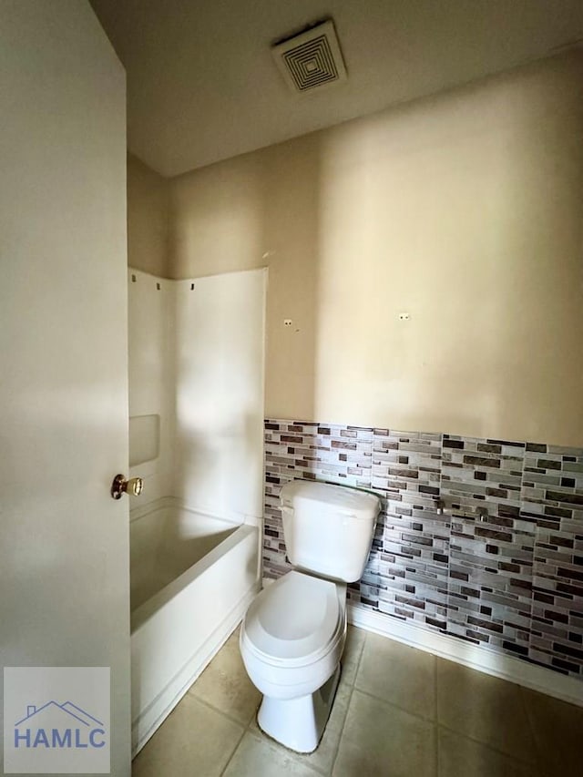 bathroom featuring toilet, a tub to relax in, and tile patterned floors