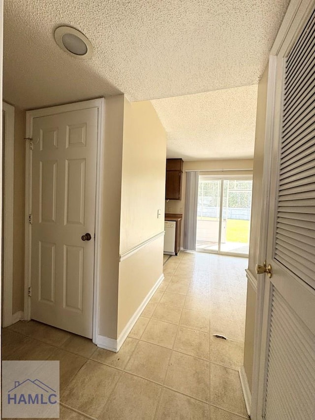 corridor with light tile patterned flooring and a textured ceiling