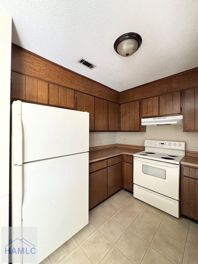 kitchen with a textured ceiling, white appliances, and light tile patterned flooring