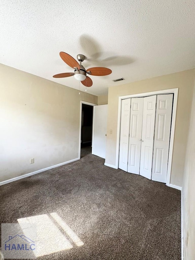 unfurnished bedroom featuring dark colored carpet, ceiling fan, a textured ceiling, and a closet