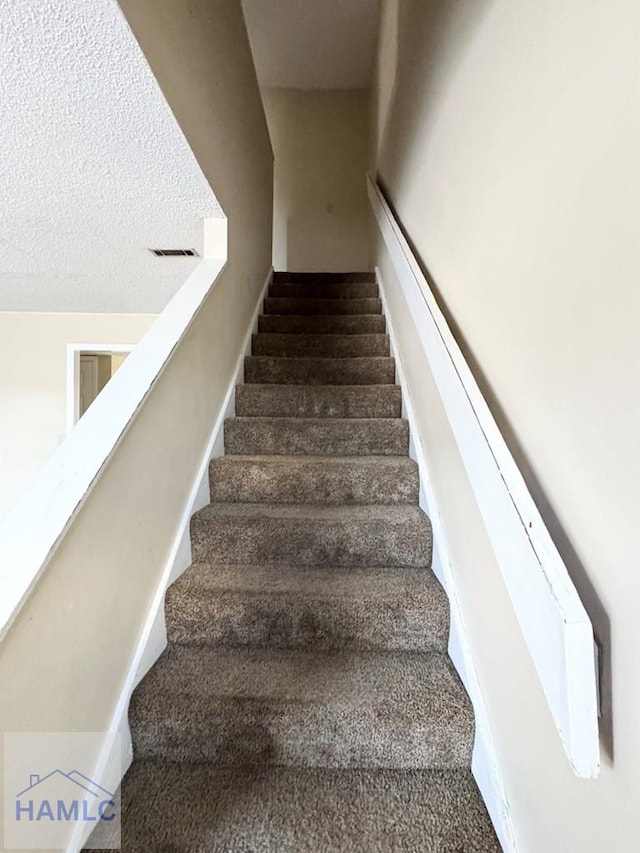 stairs featuring a textured ceiling