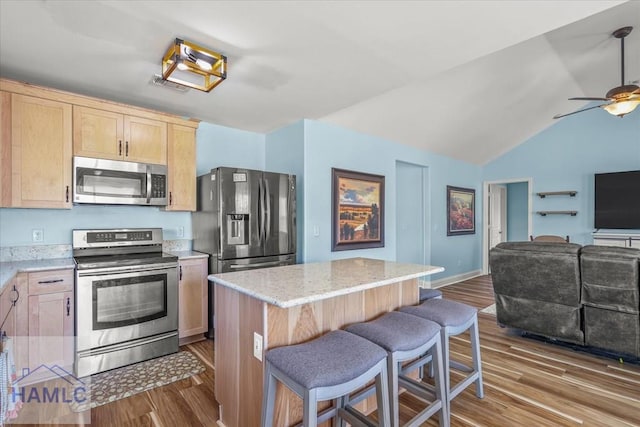kitchen featuring a ceiling fan, wood finished floors, light brown cabinetry, appliances with stainless steel finishes, and open floor plan
