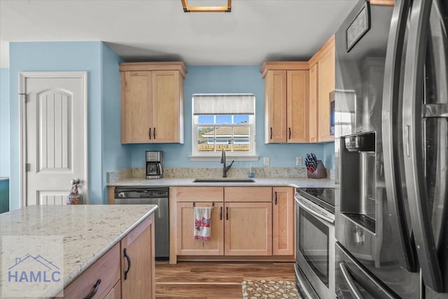 kitchen with a sink, light brown cabinets, appliances with stainless steel finishes, and wood finished floors