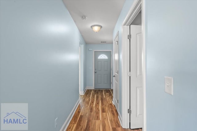 corridor featuring baseboards and wood finished floors