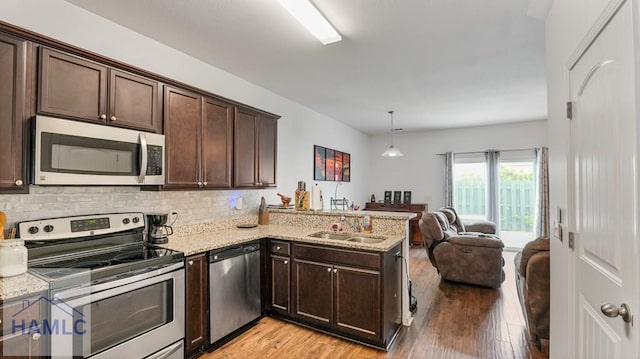25 Walker Ct, Richmond Hill, GA 31324 - kitchen featuring light wood-style flooring, a peninsula, stainless steel appliances, dark brown cabinetry, and a sink
