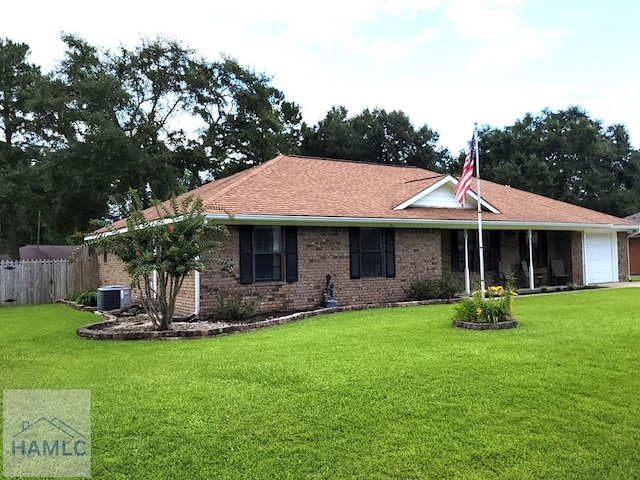 view of front facade with cooling unit, a garage, and a front lawn