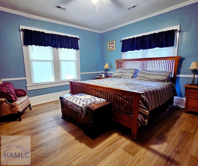 bedroom with ceiling fan, hardwood / wood-style flooring, ornamental molding, and a textured ceiling